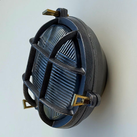 Dark gray cast iron wall light with brass hardware and ribbed glass lens nautical bulkhead wall light design