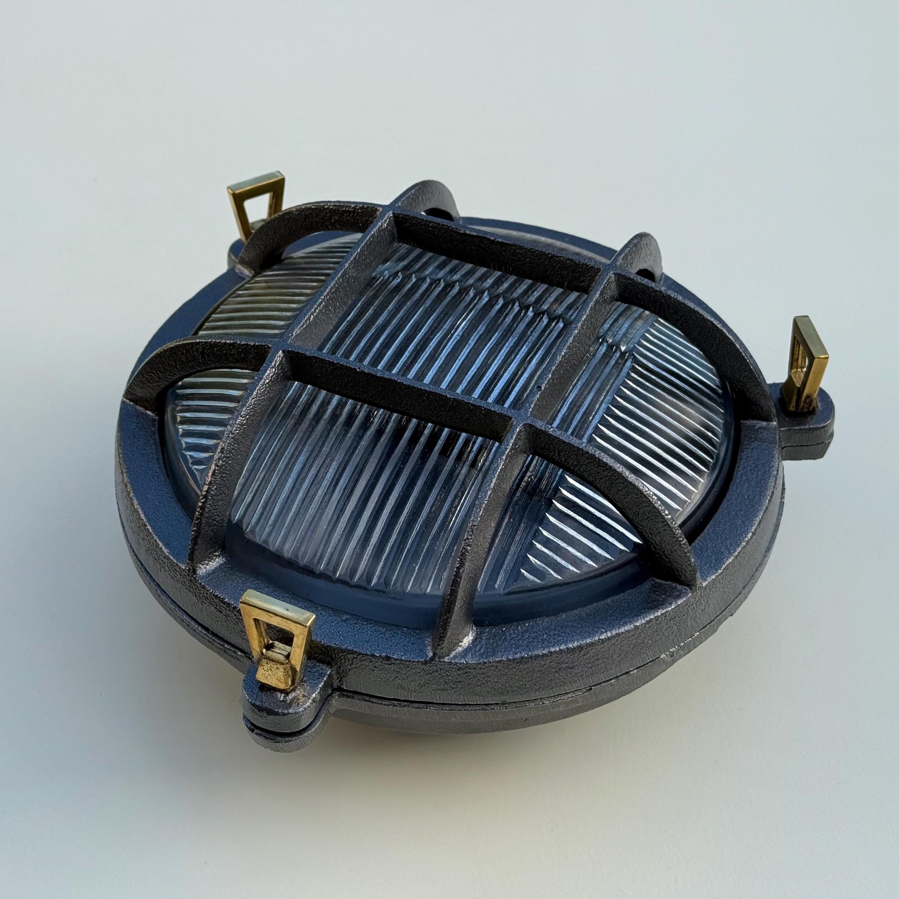 Dark gray cast iron wall light with gold-tone brackets and ribbed glass panel in a wroxham nautical bulkhead wall light design