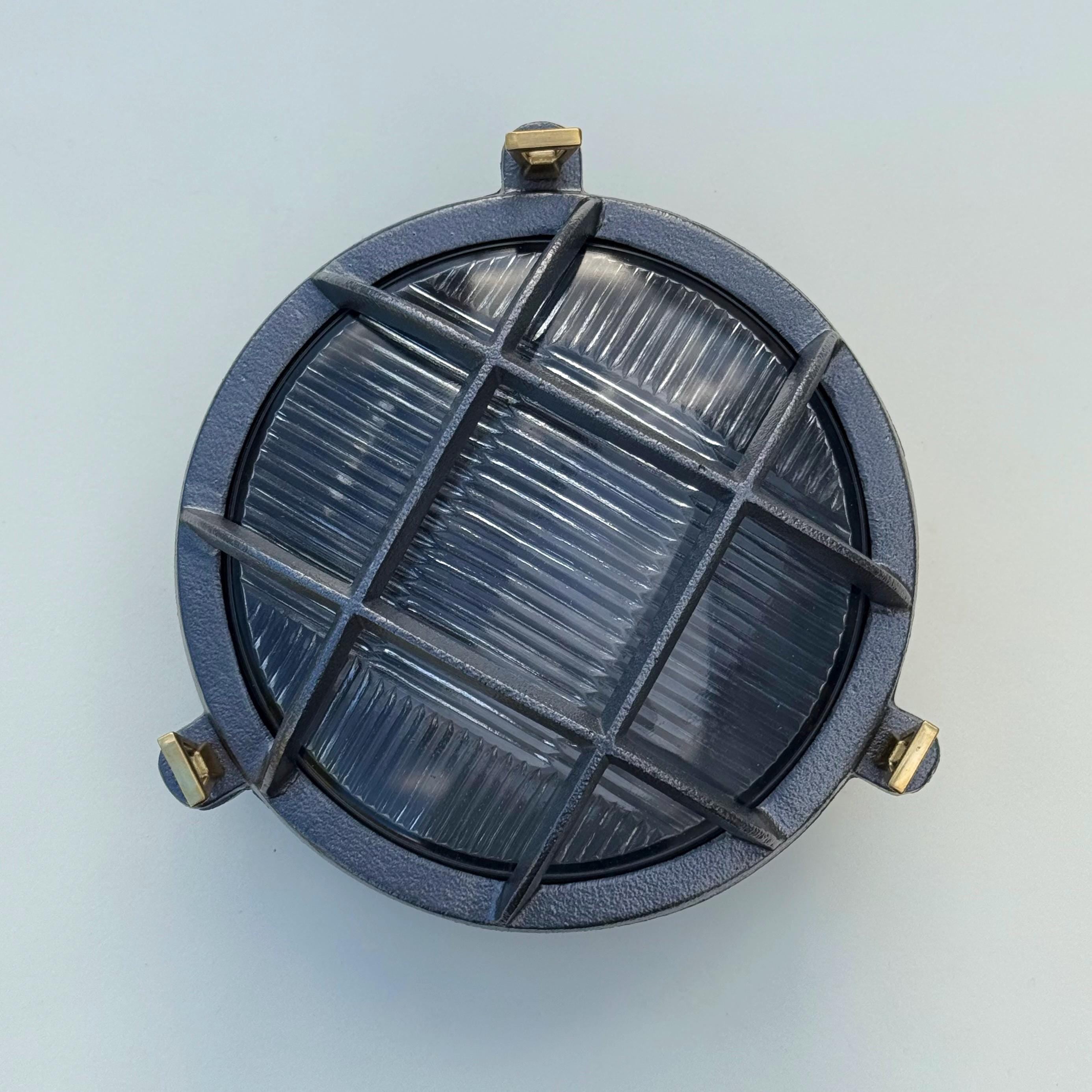 Dark gray industrial wall light with ribbed glass panel and brass hardware perfect as a nautical bulkhead wall light