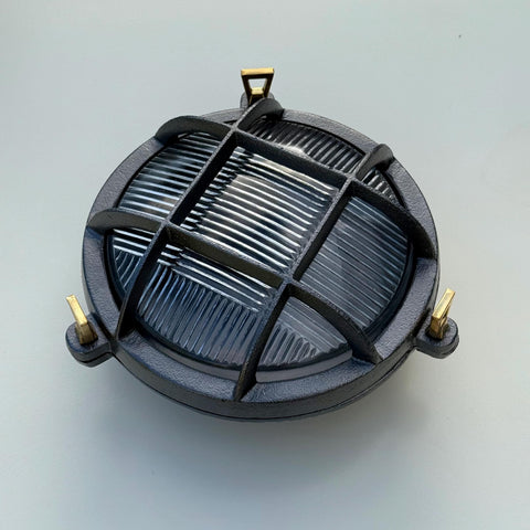 Black cast iron wall light with brass brackets and ribbed glass panel perfect as a nautical bulkhead wall light