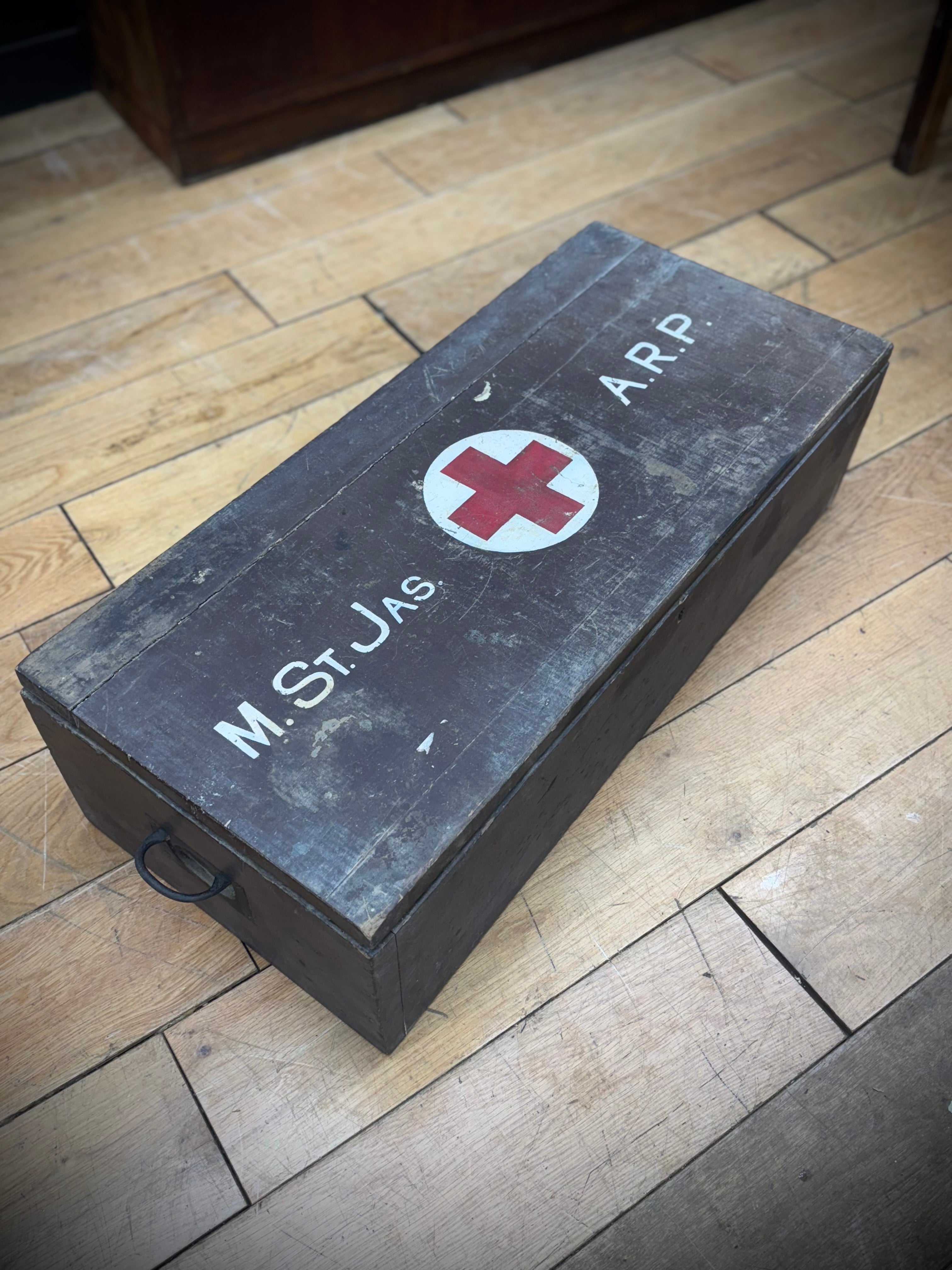 Dark gray wooden civil defence aid box with red cross emblem and white lettering vintage wartime medical case