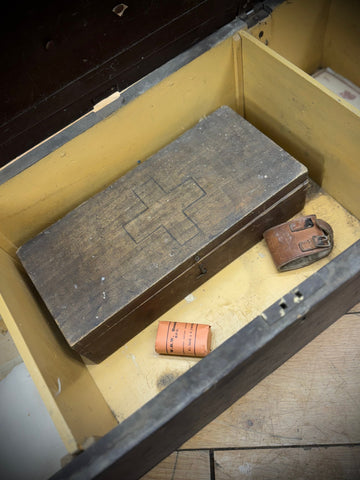 A weathered dark brown wooden wwii aid box with a raised red cross emblem for civil defence first aid use