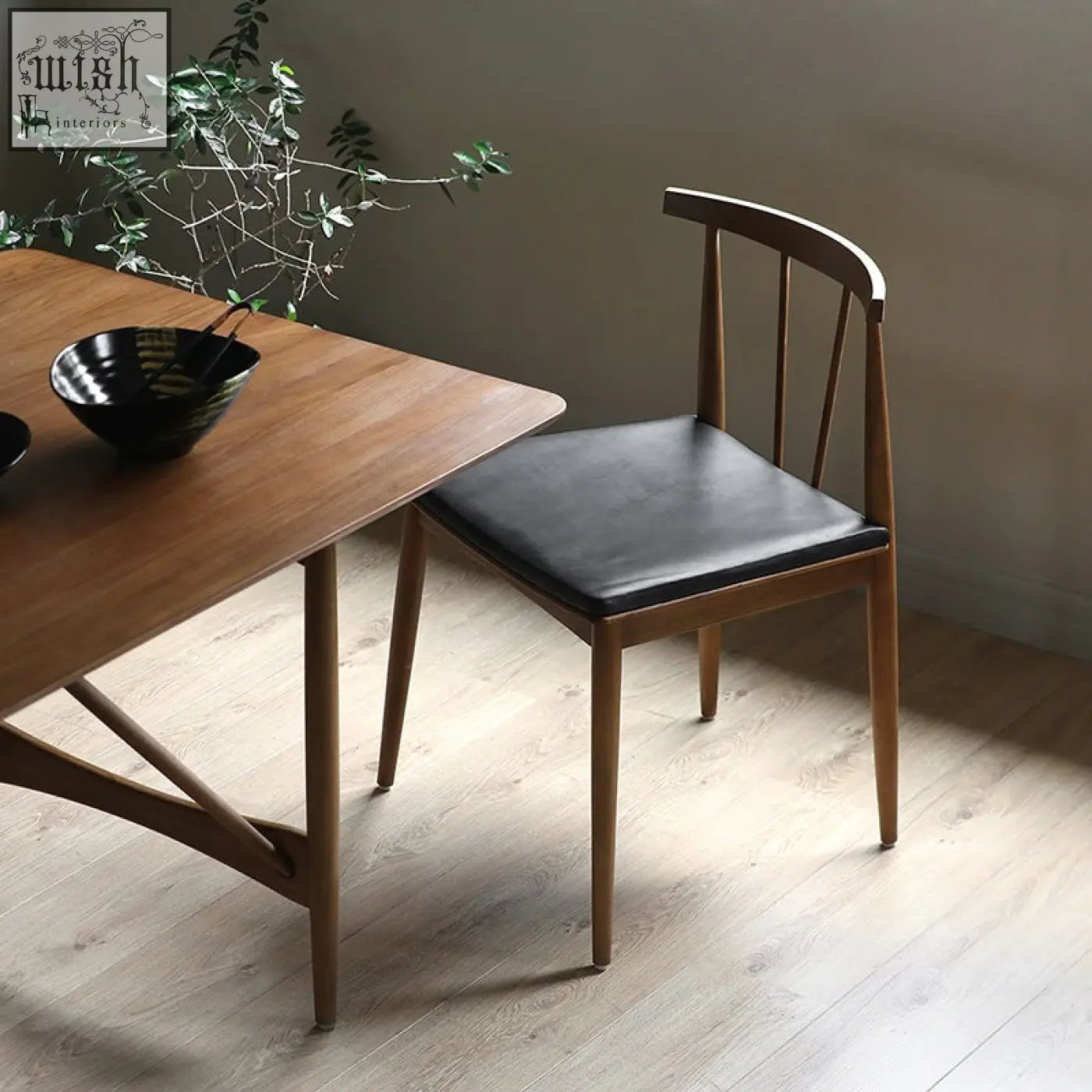 Mid-century modern wyatt dining chair with black leather seat and curved wooden backrest perfect for dining areas