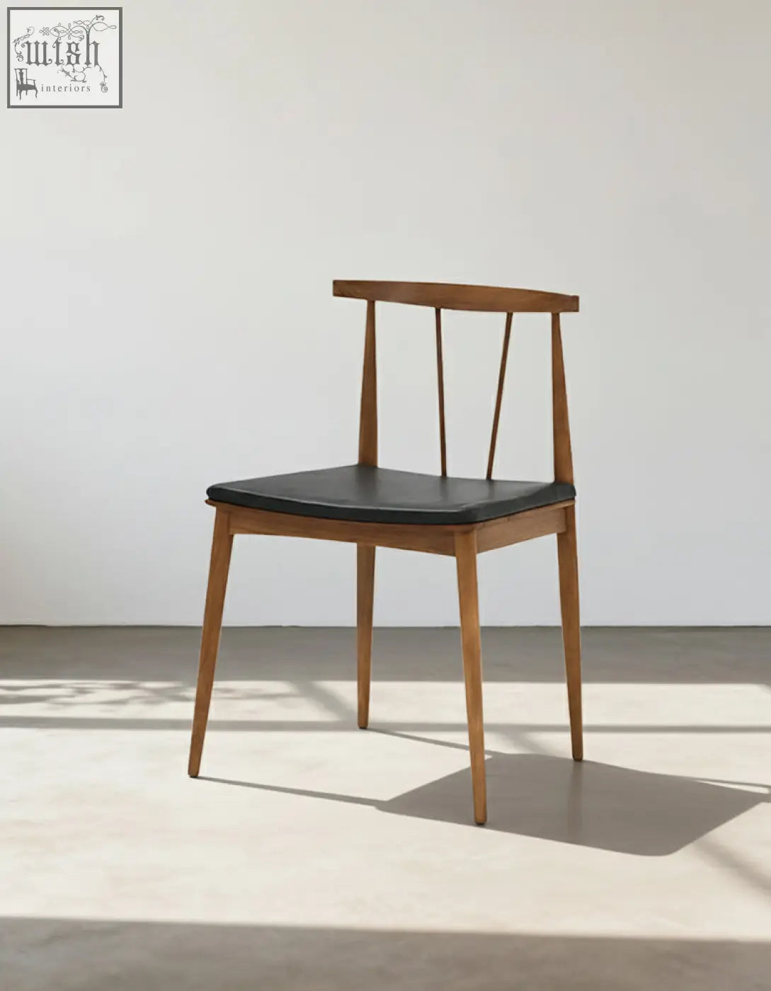 Wyatt dining chair with a minimalist wooden frame and sleek black leather seat perfect for dining areas