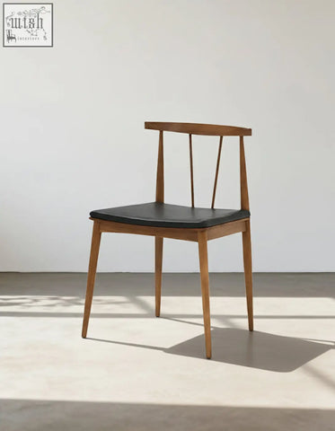 Wyatt dining chair with a minimalist wooden frame and sleek black leather seat perfect for dining areas