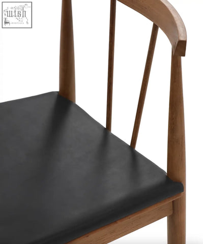 Wyatt dining chair in black with a sleek wooden frame, curved backrest, vertical spindles, and a smooth leather seat