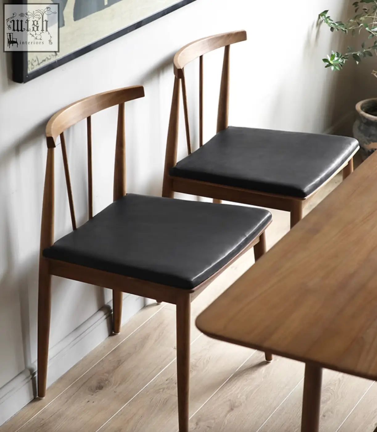 Two minimalist wyatt dining chairs with wooden frame and black leather seats perfect for dining areas