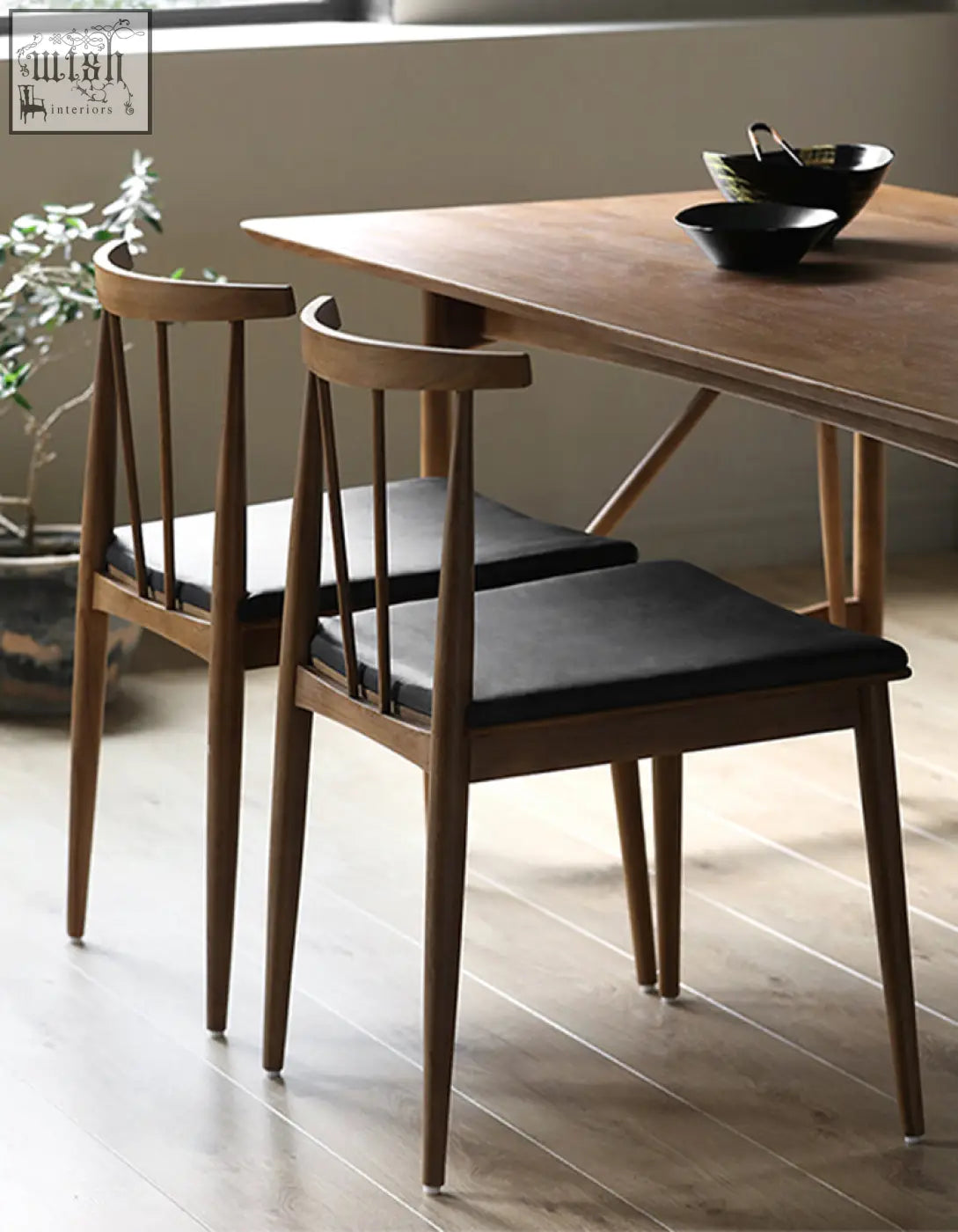 Two wyatt dining chairs with black upholstered seats and slender wooden legs perfect for dining chair setup