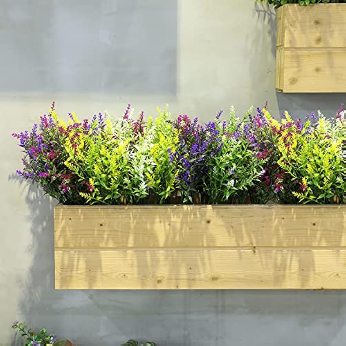 A vibrant multicolored faux flowers arrangement in a light wooden planter box ideal for outdoor fake plants decor