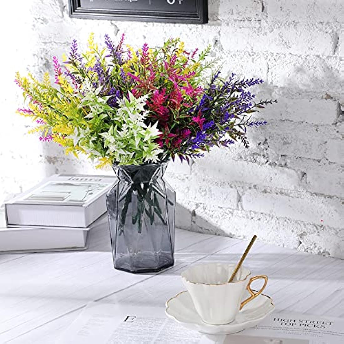 A dark gray faceted glass vase holding vibrant multicolored faux flowers from xinnun outdoor fake plants collection