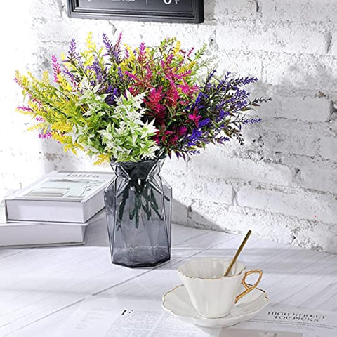 A dark gray faceted glass vase holding vibrant multicolored faux flowers from xinnun outdoor fake plants collection