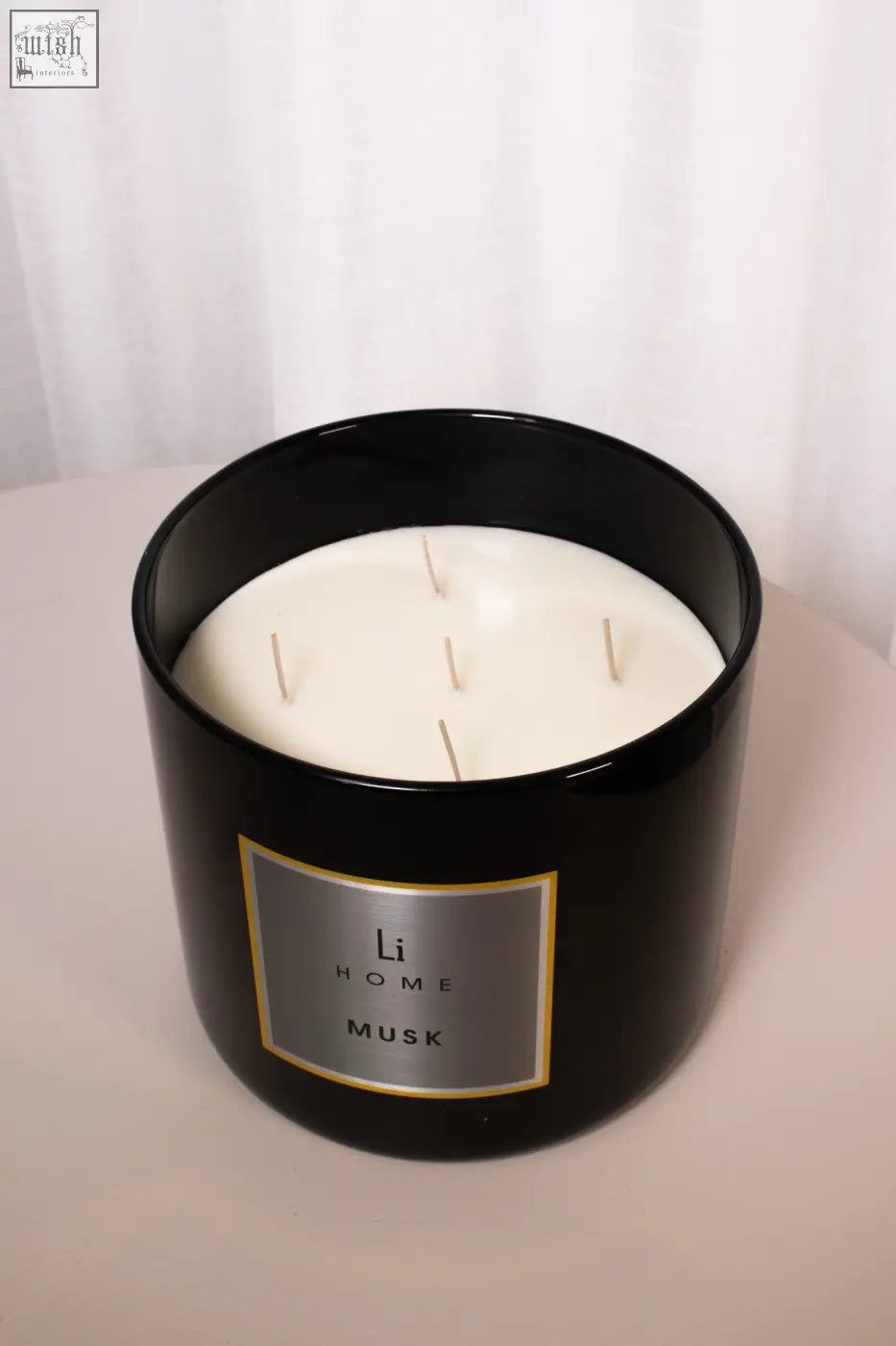 Black cylindrical candle jar with creamy white wax and four wicks scented with white musk in xl candle musk