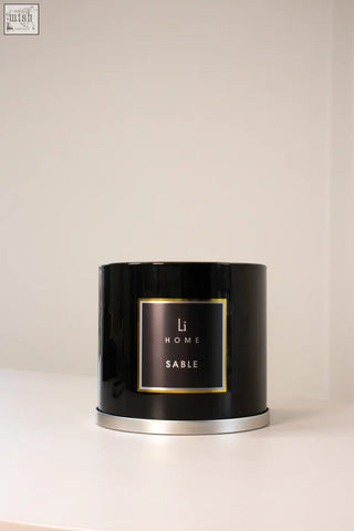 Black cylindrical xl candle in a glossy tin with gold trimmed li home sable label for cozy ambiance