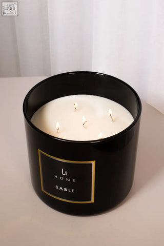 Black cylindrical xl candle jar with gold trim label sable and four lit white candles inside