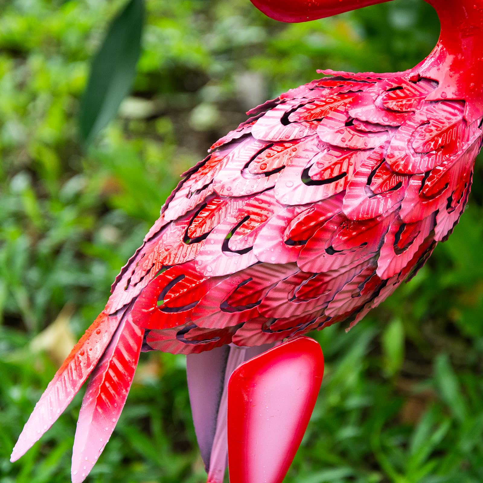 A vibrant red metal flamingo statue with glossy finish and intricate feather cut details perfect for garden decor