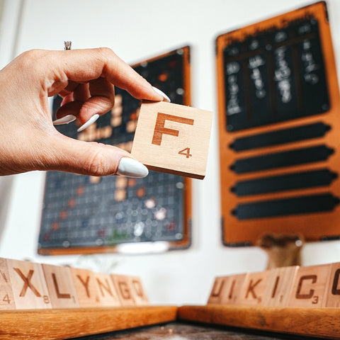 A light brown wooden scrabble tile with the letter f and number 4 from the xxl black words game classic word game for vocabulary skills