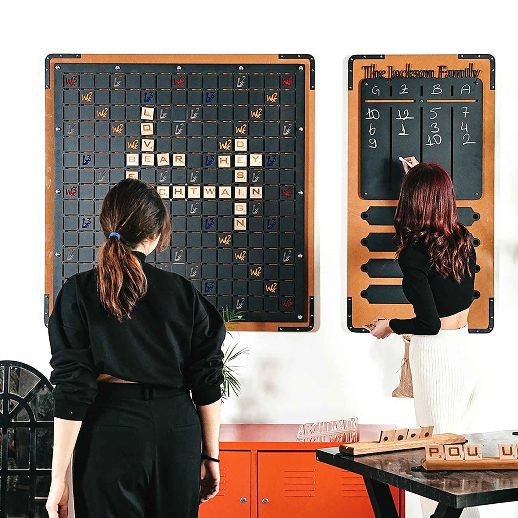 Wall-mounted wooden-framed xxl black words game with black surface and colorful letter tiles for classic word game fun