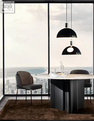 Black dome pendant lights with metallic fixtures hang above a modern dining table with velvet dining chairs
