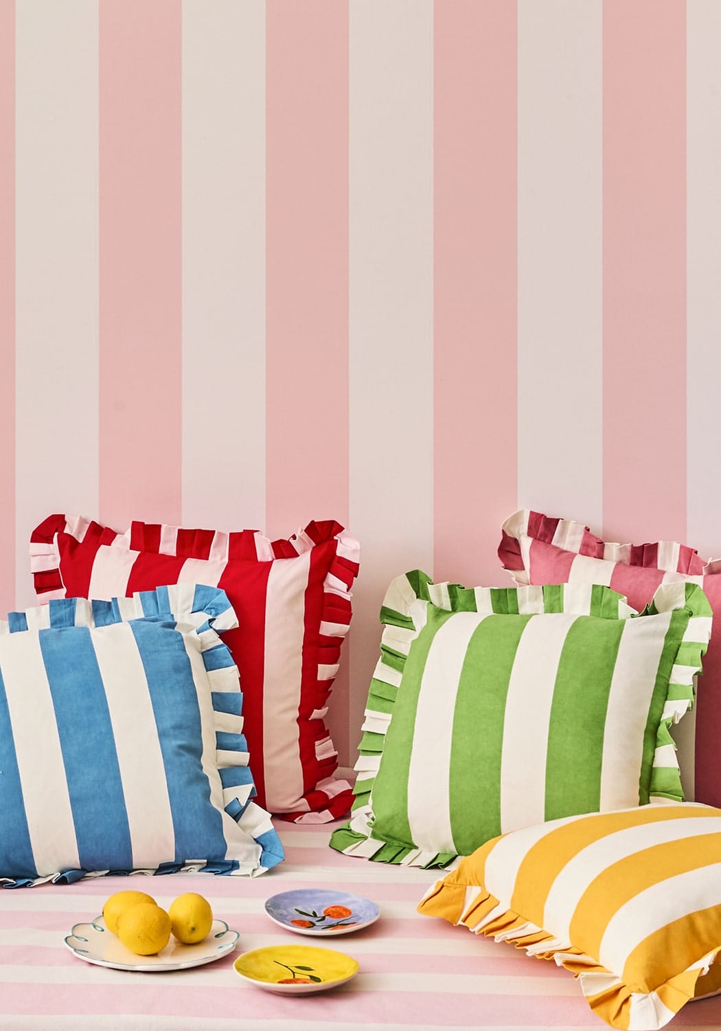 A collection of colorful ruffled pillowcases in bold red white blue white green white and yellow white stripes with a retro vibe