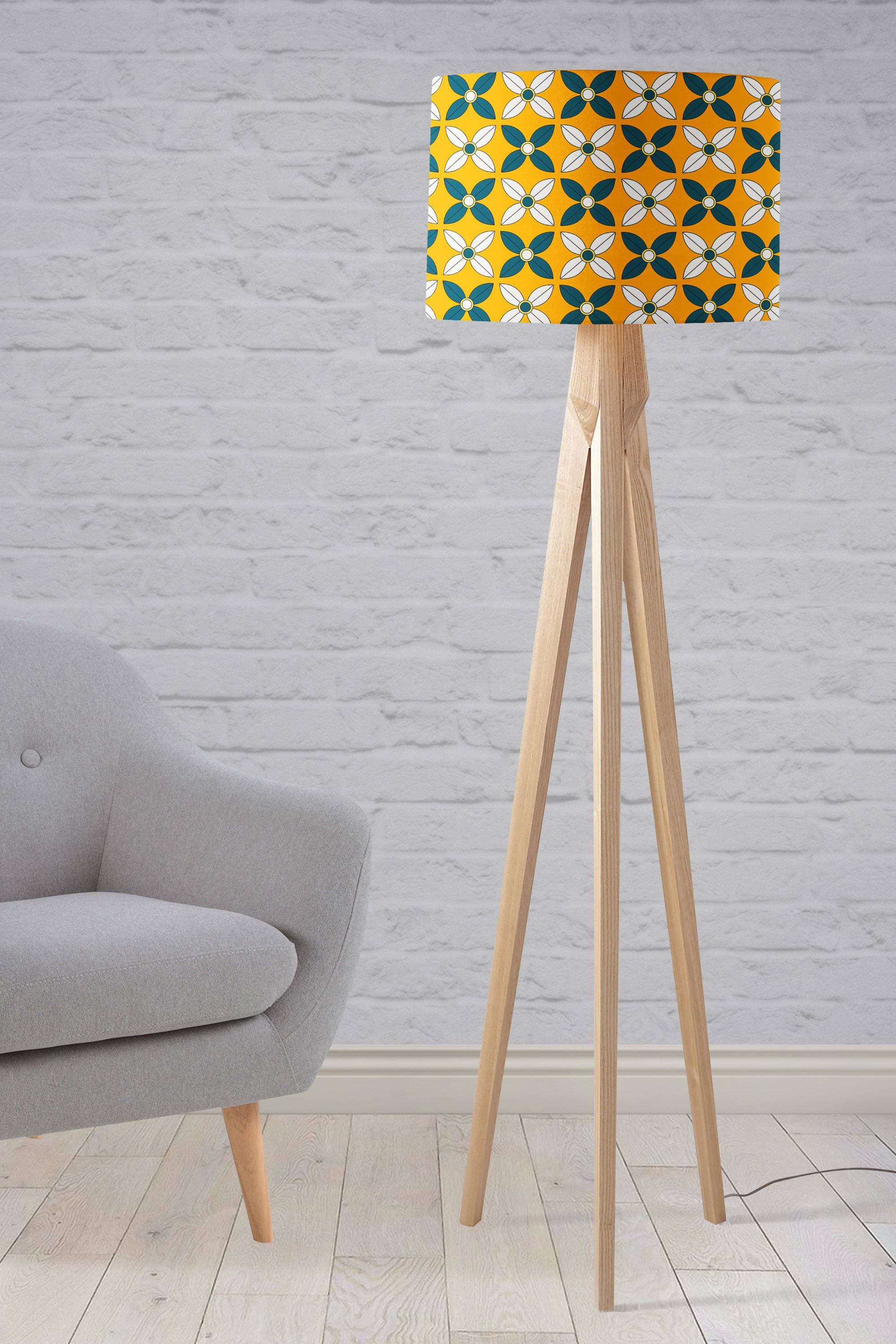 A yellow lampshade with a retro blue and white design on a wooden tripod base perfect for a table lamp