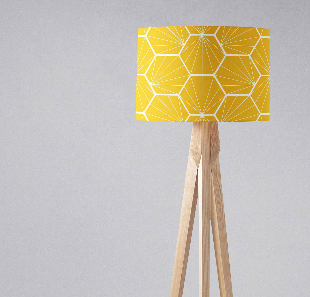 A vibrant yellow table lamp with a white hexagon design lampshade on a light wood tripod base with inch diameter