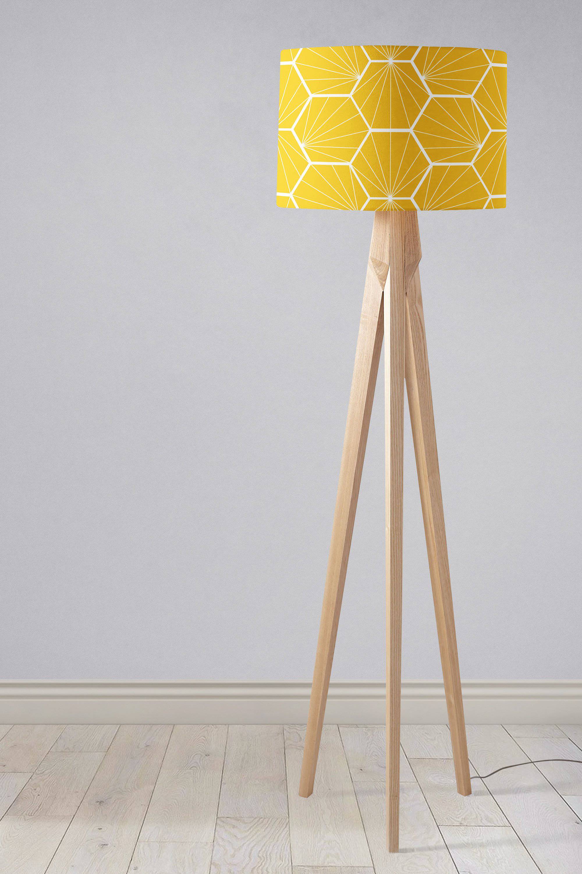 A modern table lamp with a yellow lamp shade featuring white hexagon design and light wood tripod legs, inch diameter shade