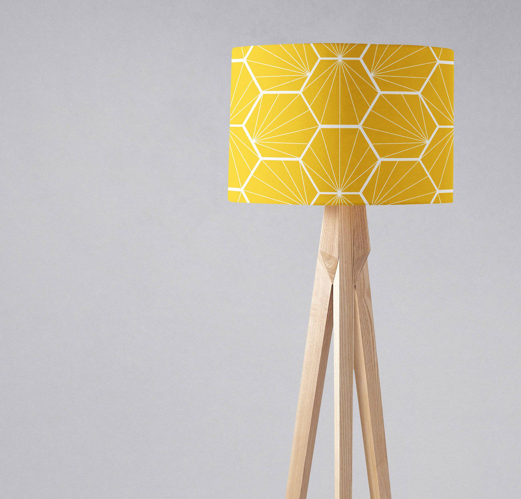 A vibrant yellow table lamp with a white hexagon patterned lamp shade on a light wooden tripod base, inch diameter