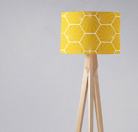 A vibrant yellow table lamp with a white hexagon patterned lamp shade on a light wooden tripod base, inch diameter