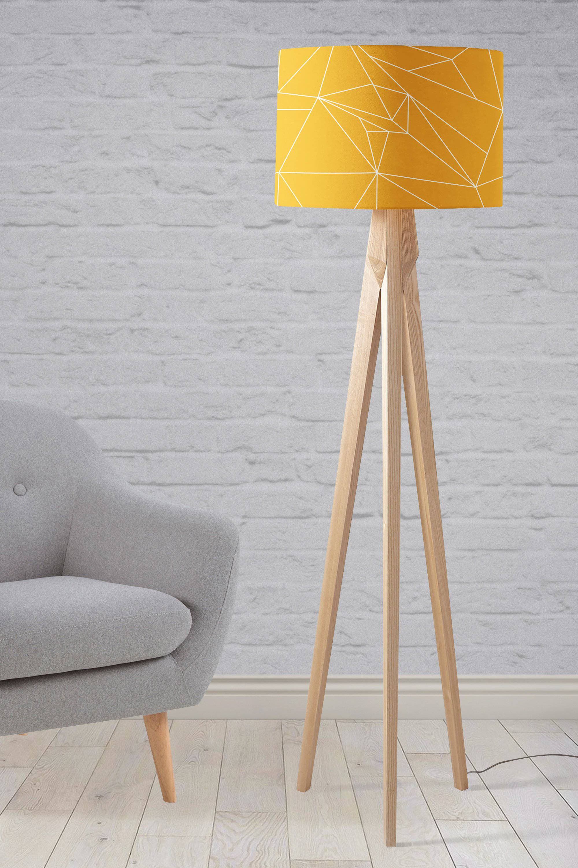 A vibrant yellow table lamp shade with white geometric design on a light wood tripod base for ceiling or table use