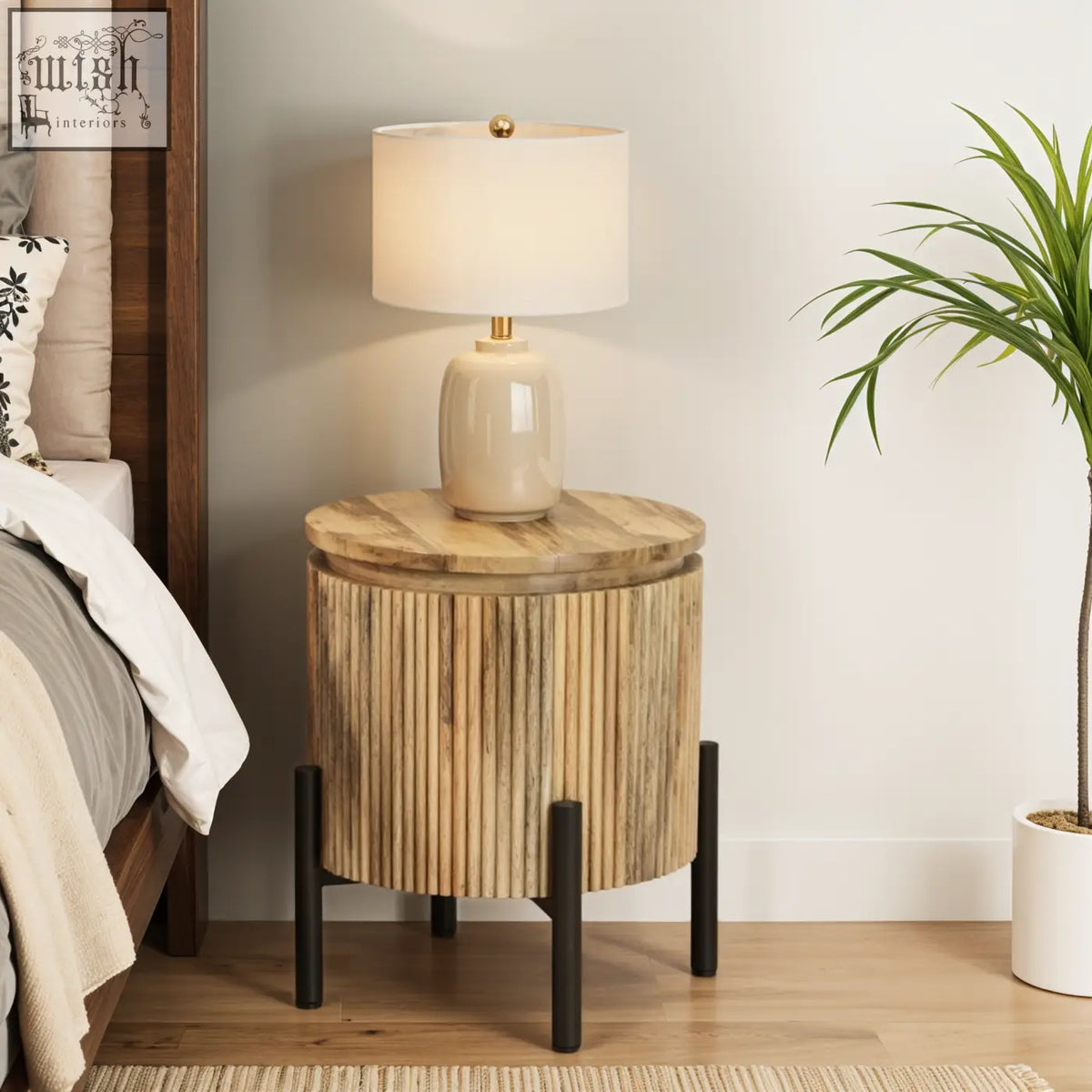 A york solid bedside table made of solid wood with vertical slats and black metal legs topped with a beige lamp