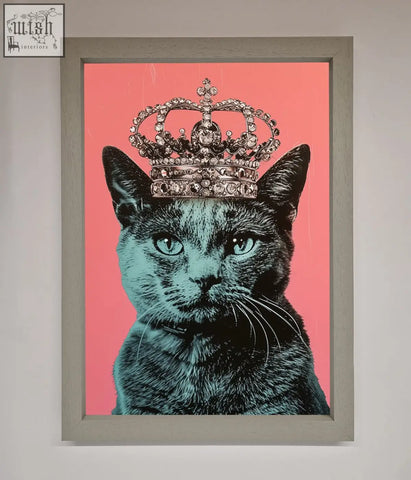 A majesty cat framed print of a black cat with teal eyes and jeweled crown on a vibrant pink background