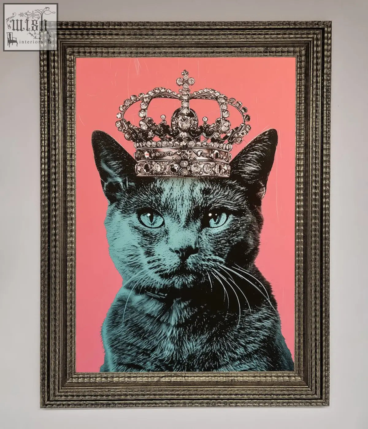 A framed print of a majesty cat framed showing a black cat with teal eyes and a silver crown on a pink background