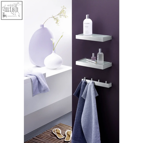 Silver metallic linea bathroom shelf in brushed stainless steel holding toiletries and towels on the wall