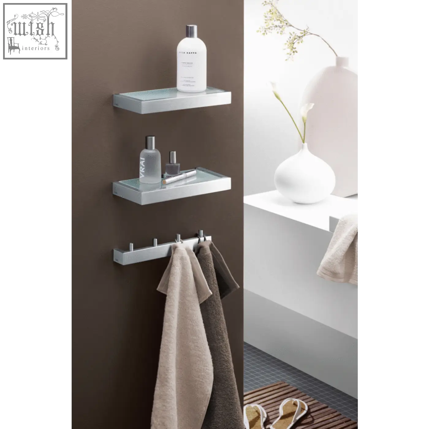 Modern chrome linea bathroom shelf with glass surface holding toiletries and towels in brushed stainless steel