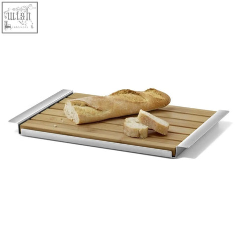 Rectangular panas breadboard with stainless steel edges and oiled bamboo surface holding sliced baguette