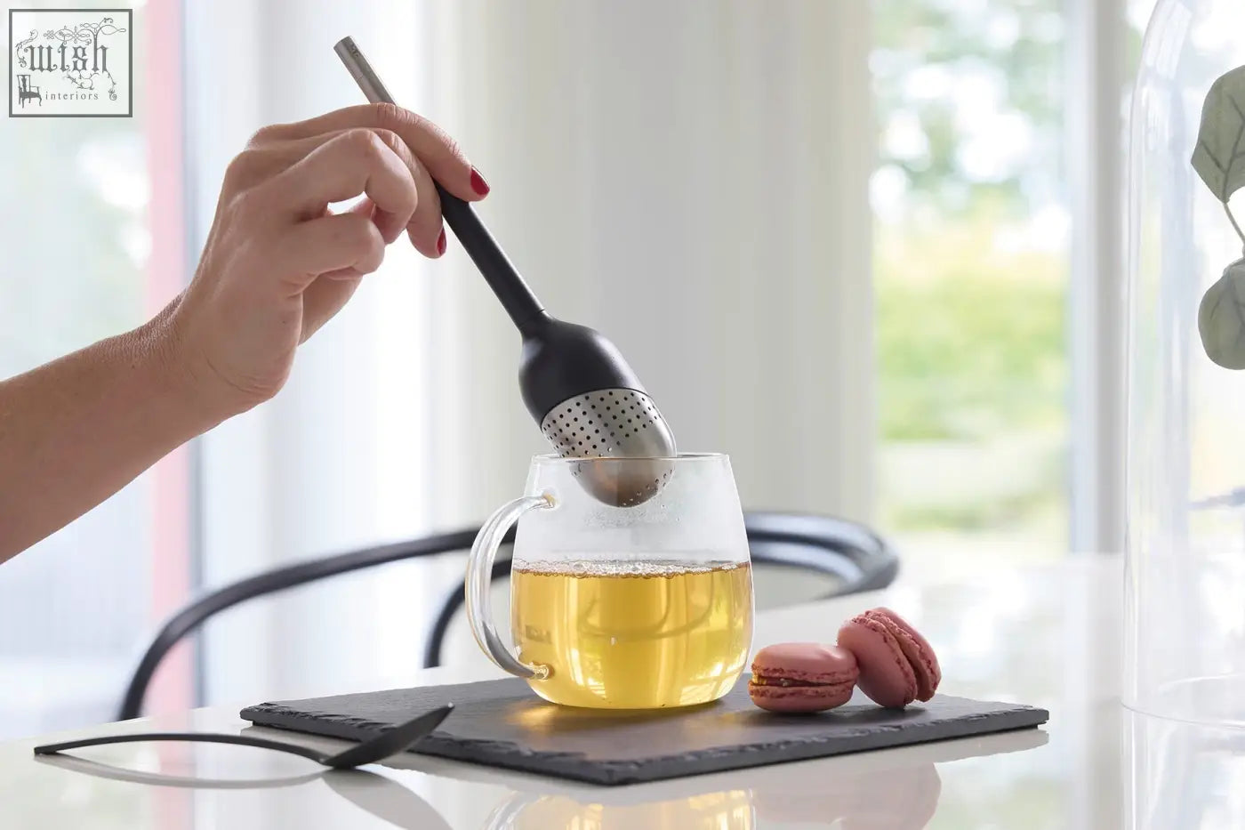 Black and silver stainless steel tea ball spoon with perforated head and sleek handle for premium tea straining