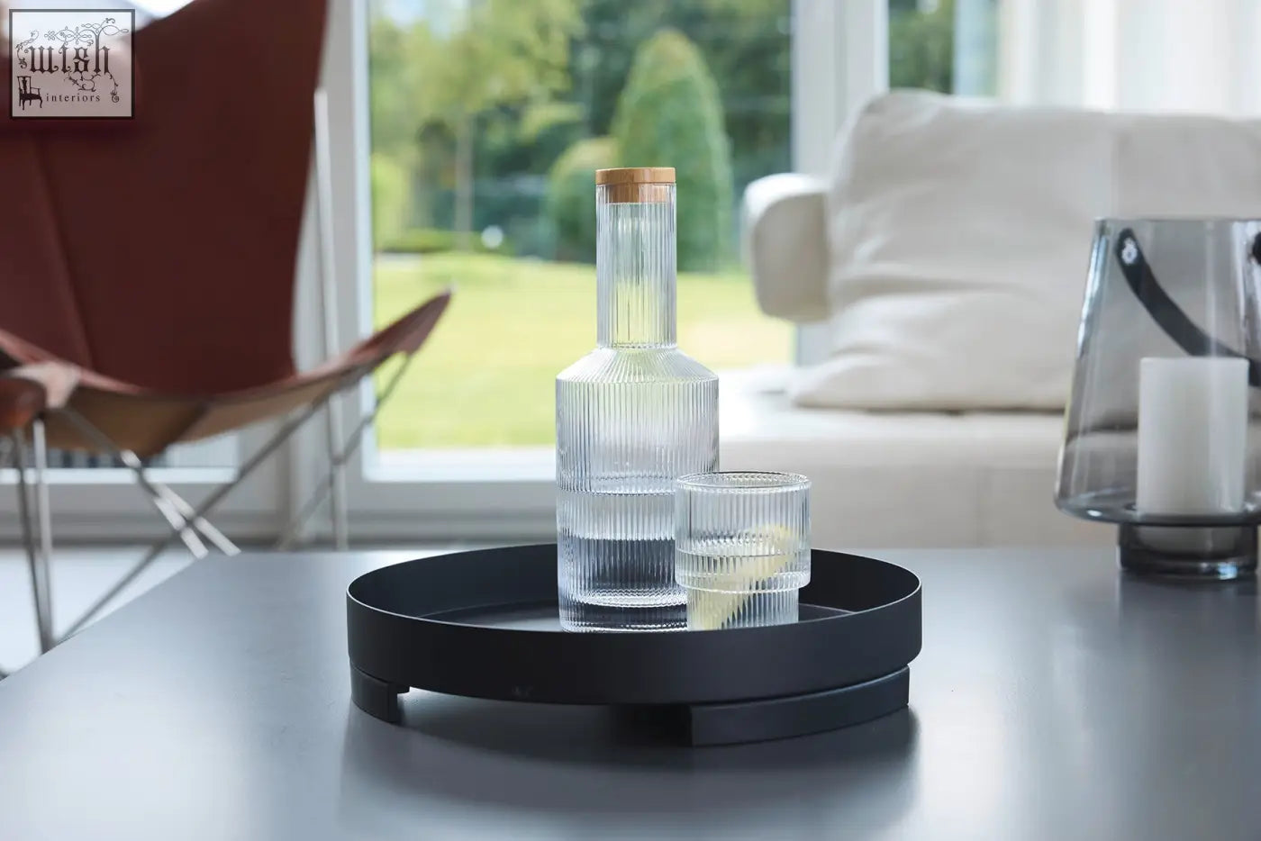 Clear glass carafe with vertical ridges and wooden cork on zack trevo black stainless steel serving tray 30cm with textured glasses