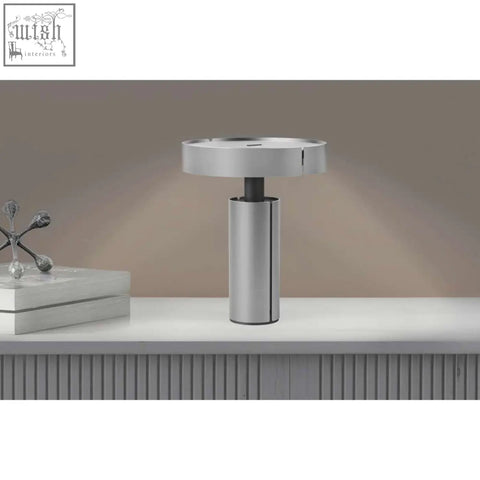 Modern silver metallic led table lamp with sleek cylindrical stainless steel base and circular top by zack yaro