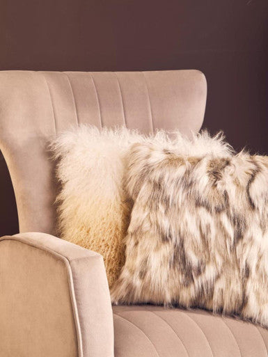 Cream-colored zamora mink velvet accent chair with gold finish legs and two fluffy throw pillows in soft hues