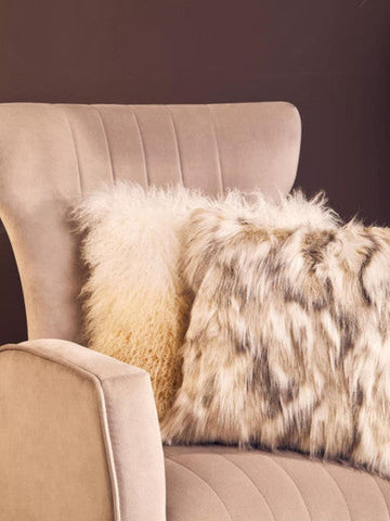 Cream-colored zamora mink velvet accent chair with gold finish legs and two fluffy throw pillows in soft hues