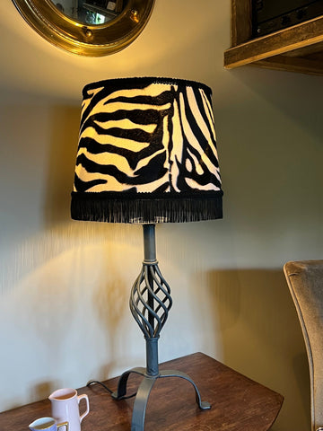 Zebra print velboa french drum lampshade with black fringe, braid, and dark metal base perfect for stylish lighting