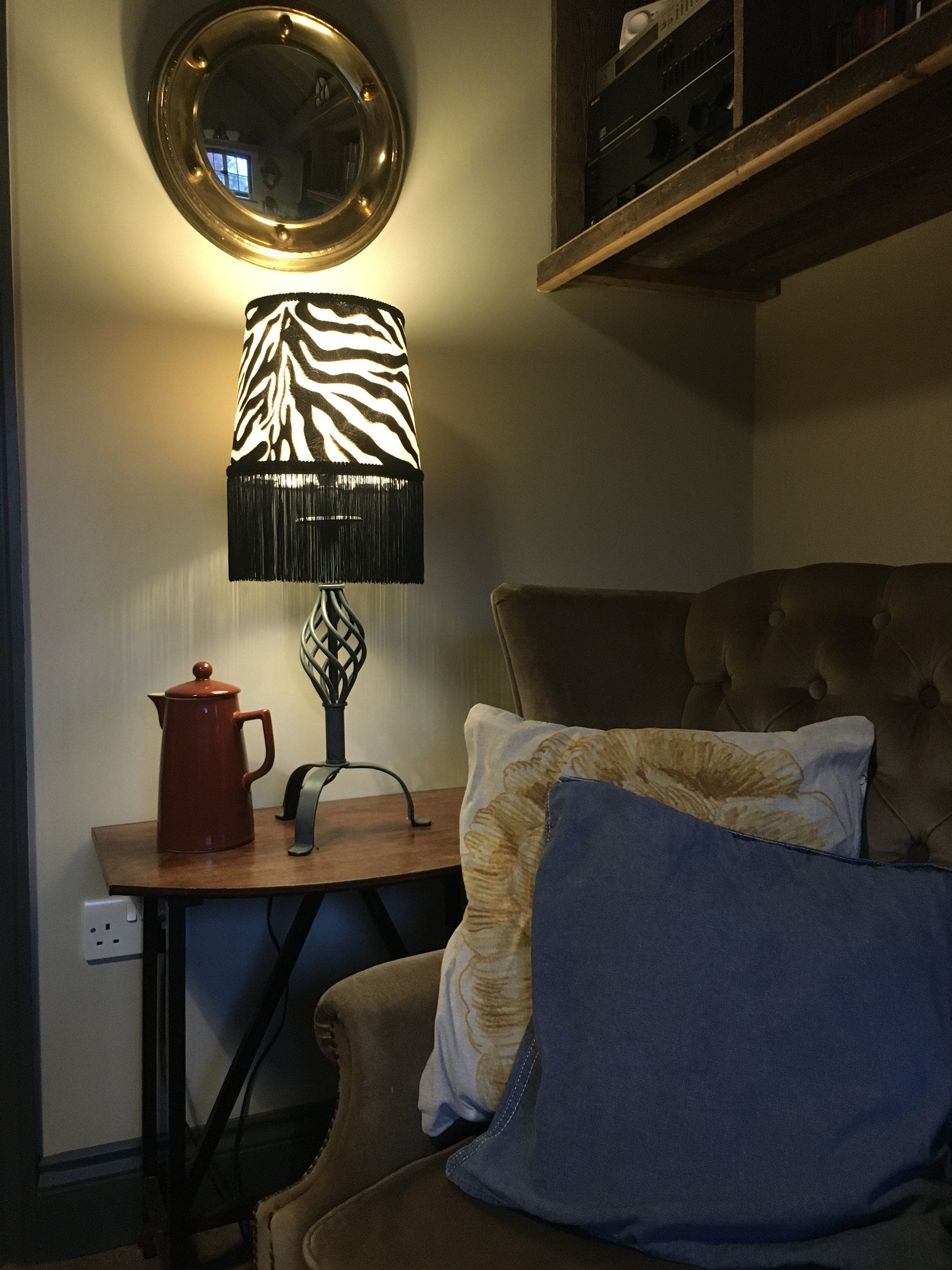 Zebra print velboa french drum lampshade with black fringe, braid, and dark metal base for stylish lighting