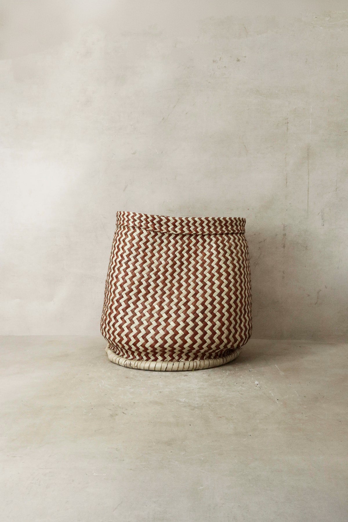 A zig zag woven planter basket in earthy brown and cream tones made from natural fibers from malawi