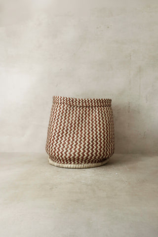 A zig zag woven planter basket in earthy brown and cream tones made from natural fibers from malawi