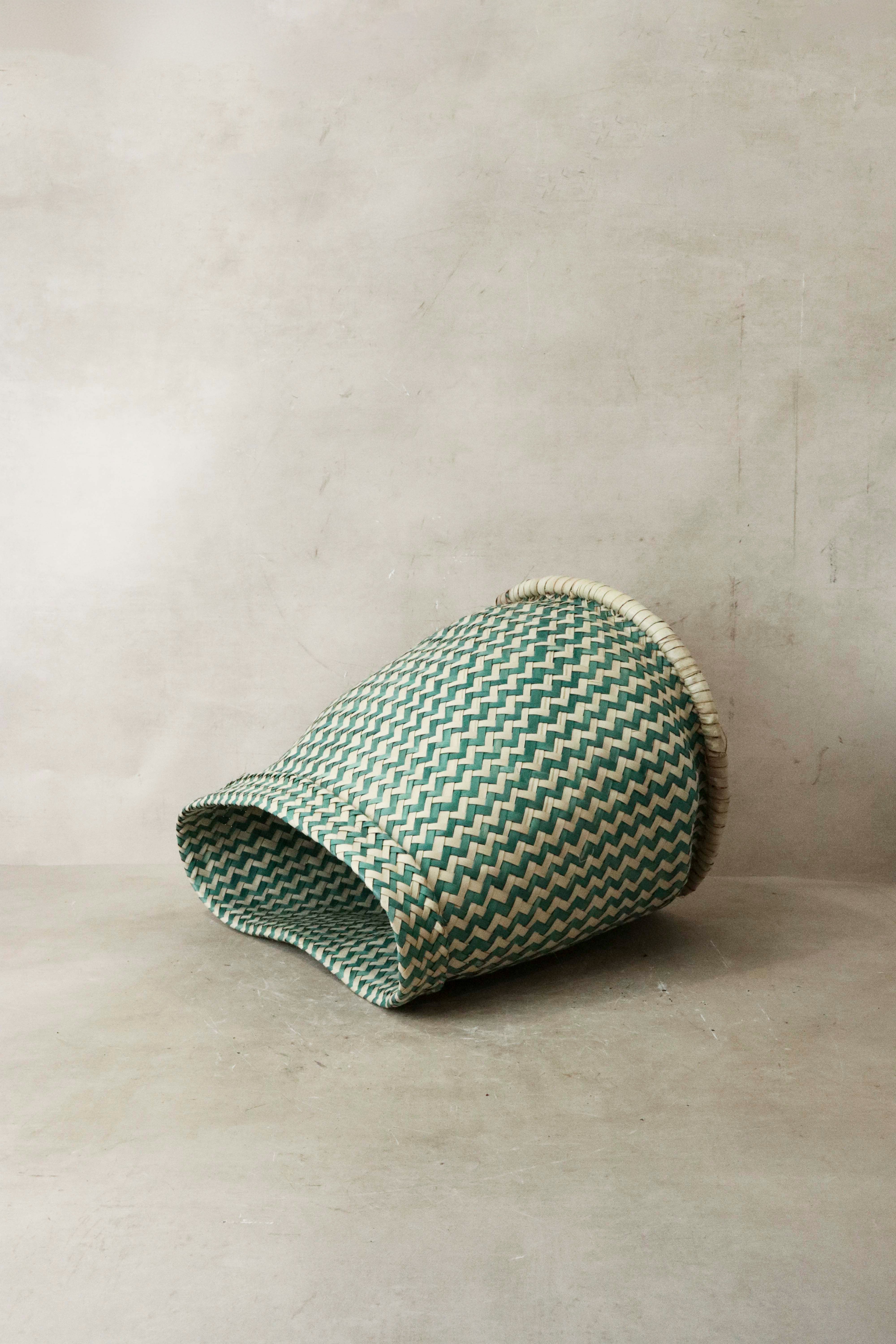 A green and white zigzag woven planter basket with a natural fiber rim from malawi for indoor plants