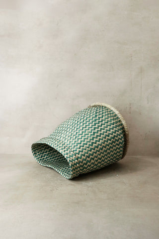 A green and white zigzag woven planter basket with a natural fiber rim from malawi for indoor plants