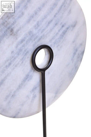 A zoro extra large white marble disc sculpture with a sleek circular extra large round board on a black metal stand