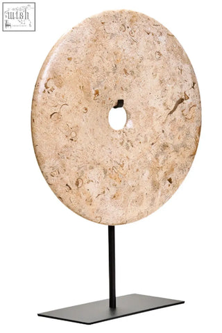 Beige large natural speckled marble disc sculpture with central hole displayed on black metal stand 30cm diameter