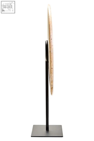A zoro large natural speckled round disc sculpture with beige marble finish on a sleek black metal stand