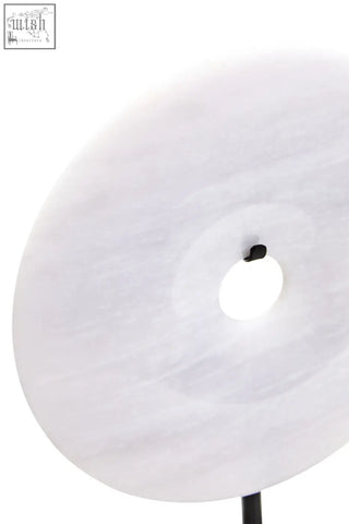 A sleek white marble zoro small round disc lamp with central cutout on a black stem round dia 20cm sculpture